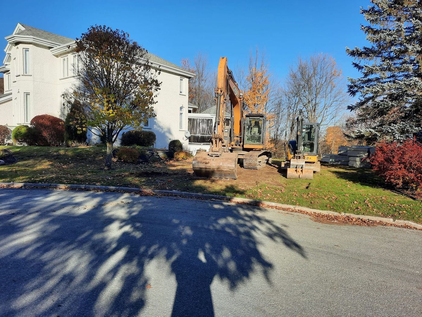 Deux excavatrice grande maison résidentielle chaussée pelouse automne