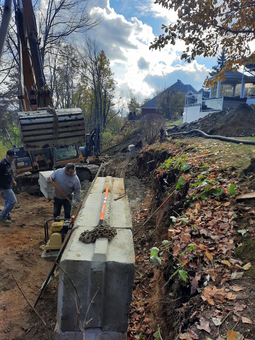 Pose dalles béton en tranchée profonde, excavatrice et deux ouvriers