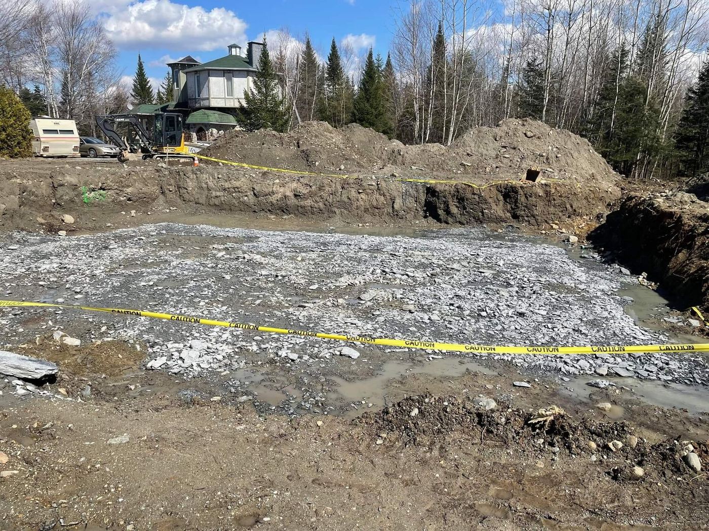 Grande excavation avec pierres concassées et ruban sécurité, fondation