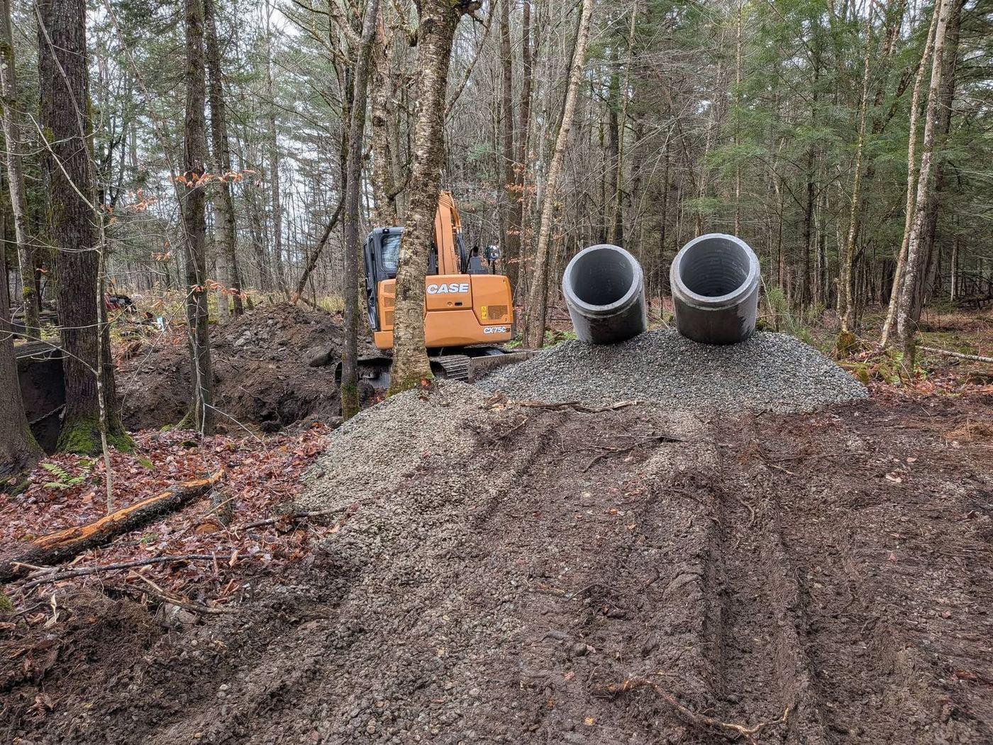 Excavatrice en forêt avec tuyaux drain, installation fosse septique