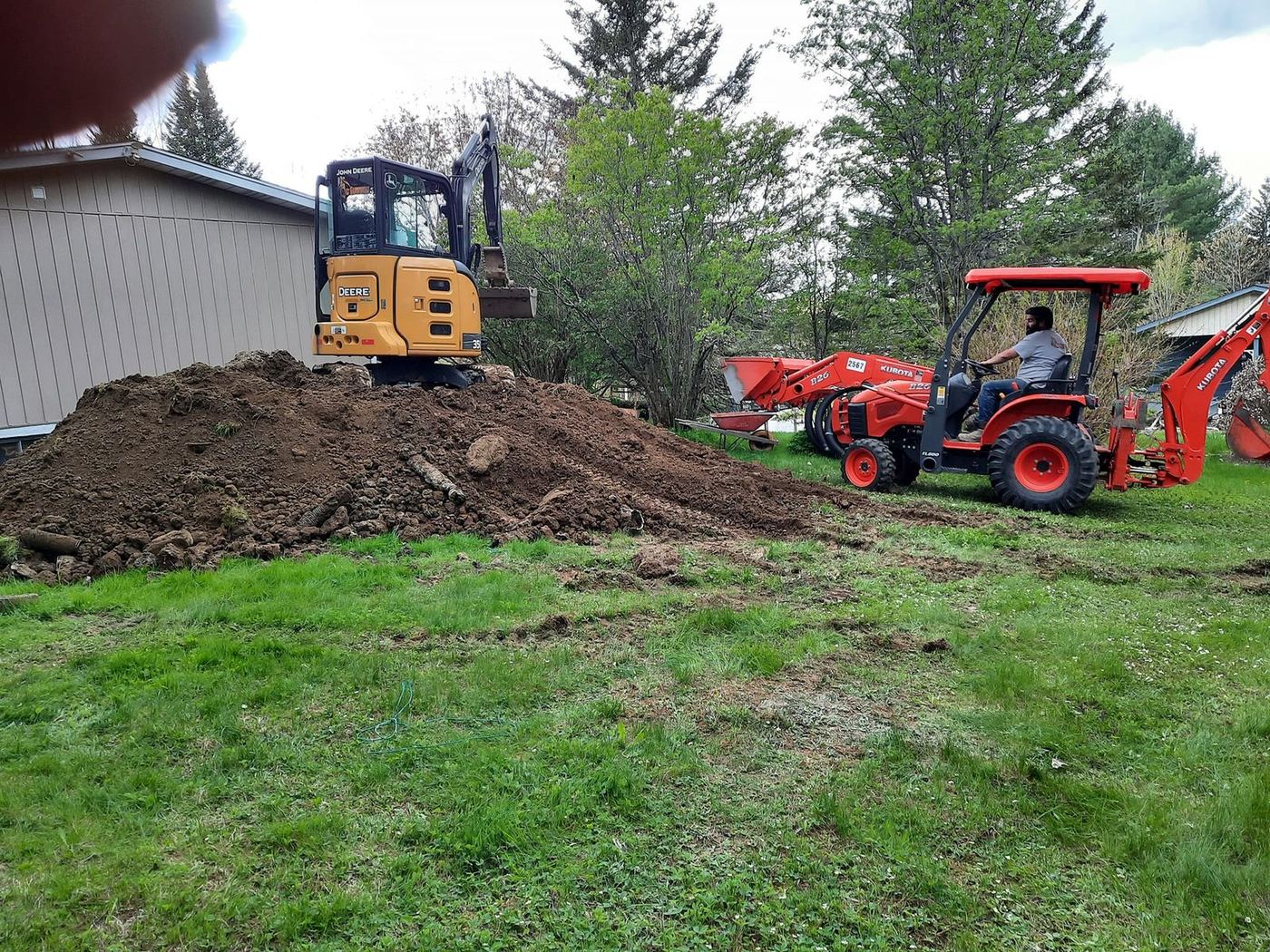 Mini-excavatrice et tracteur rouge excavent terrain résidentiel