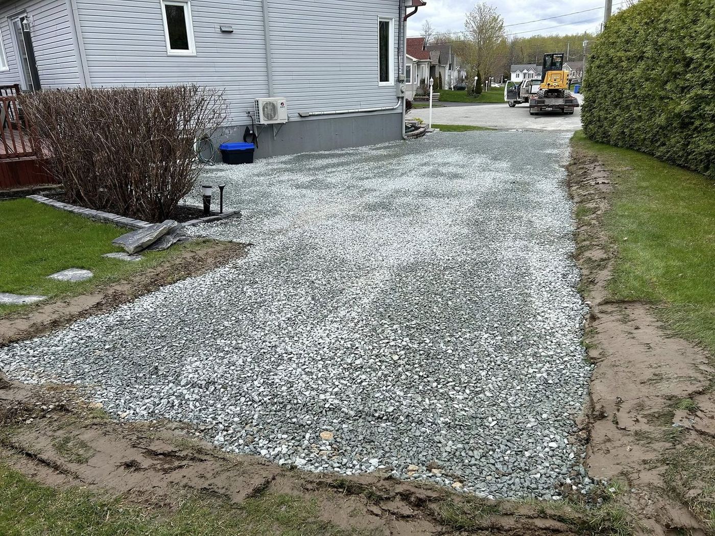 Entrée gravier résidentielle mini-excavatrice en arrière-plan