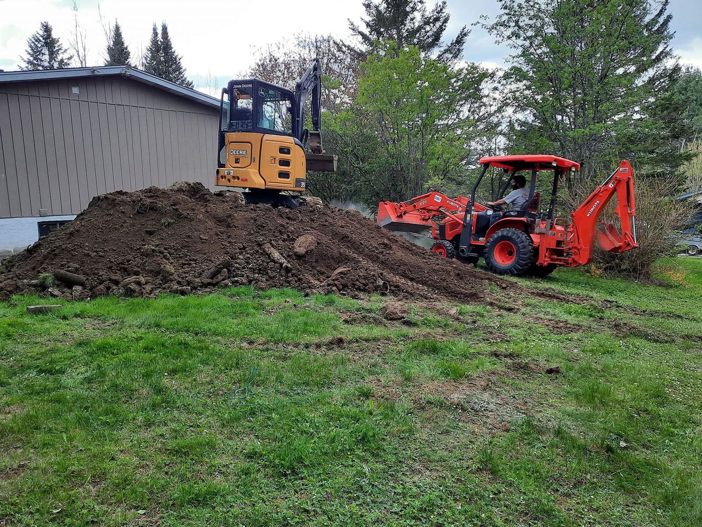 Mini-excavatrice et tracteur rouge chantier fosse septique pelouse