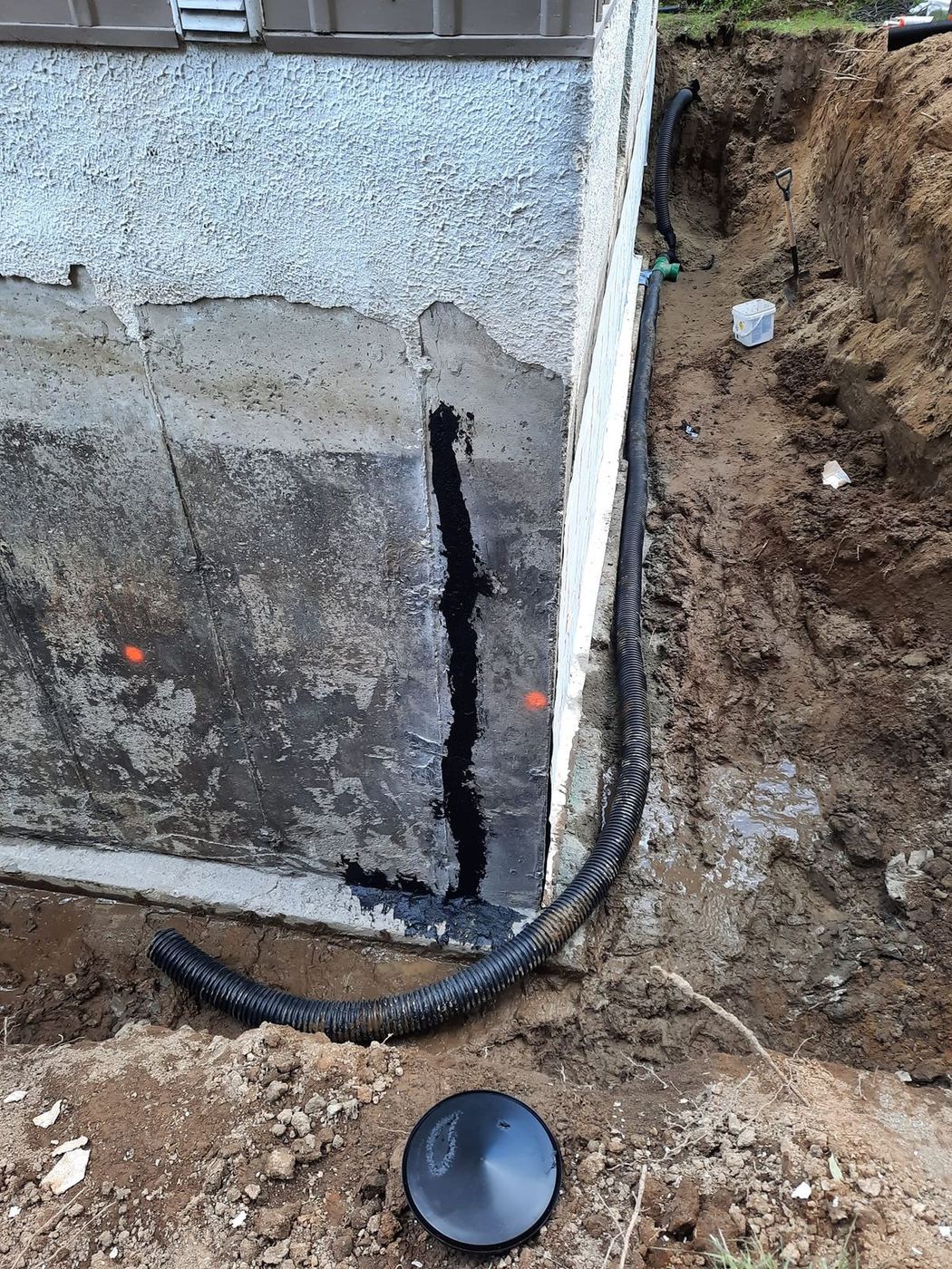 Fondation excavée tuyau drainage membrane noire réparation