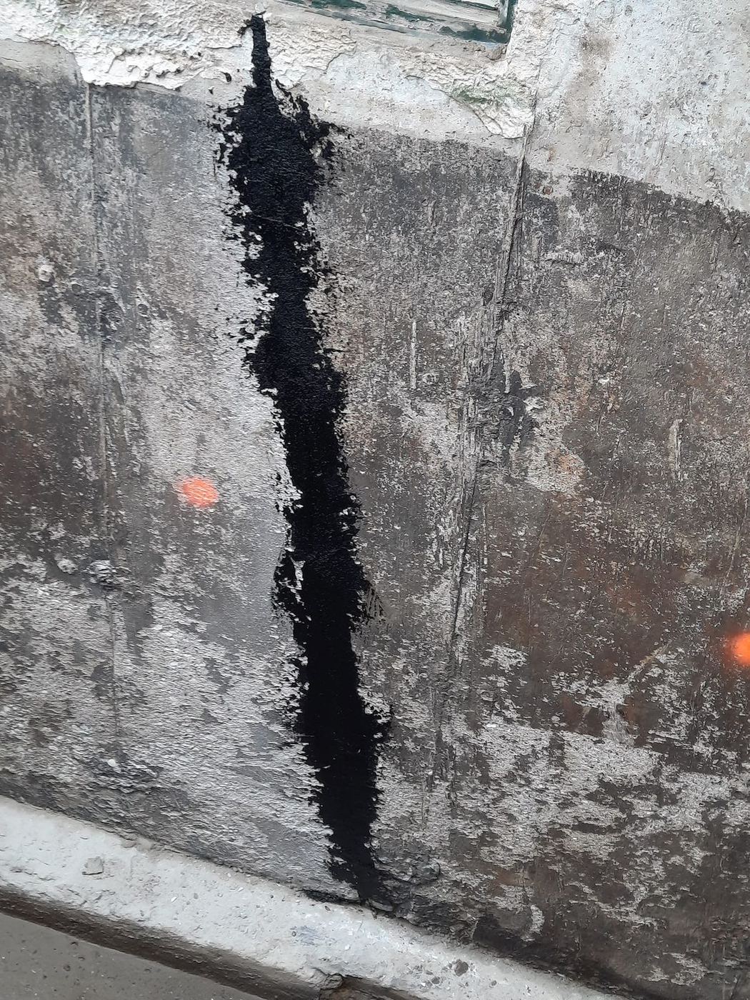 Gros plan fissure fondation béton réparée membrane noire