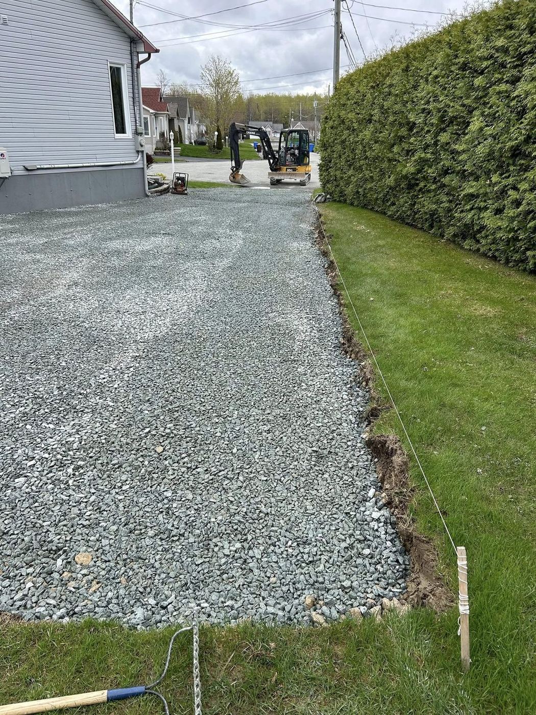 Entrée résidentielle gravier gris étalé mini-excavatrice