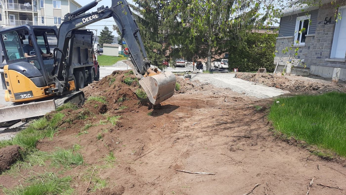 Mini-excavatrice Deere creuse entrée résidentielle maison pierre