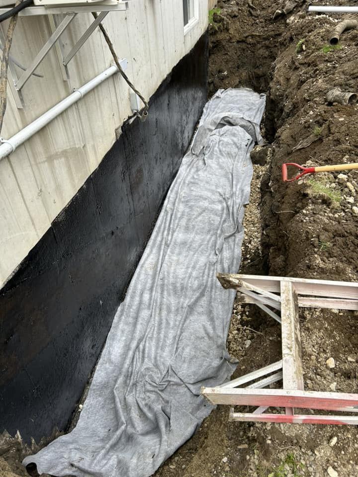 Tranchée fondation résidentielle avec membrane imperméabilisation noire