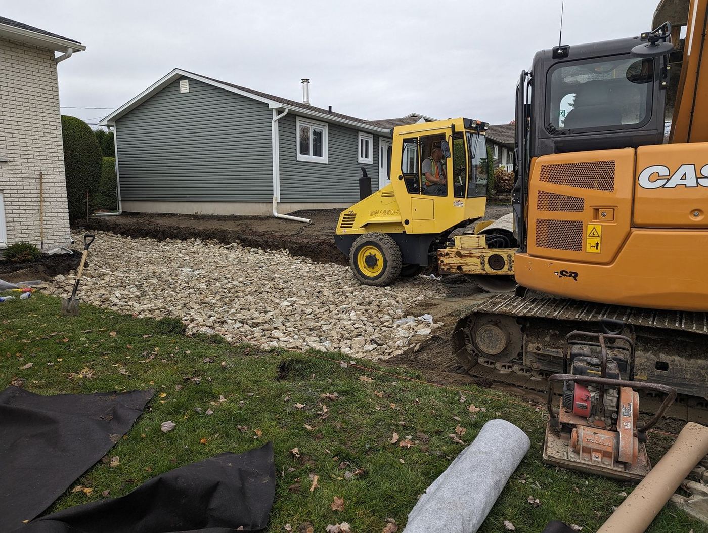 Compacteur et excavatrice sur lit de gravier résidentiel