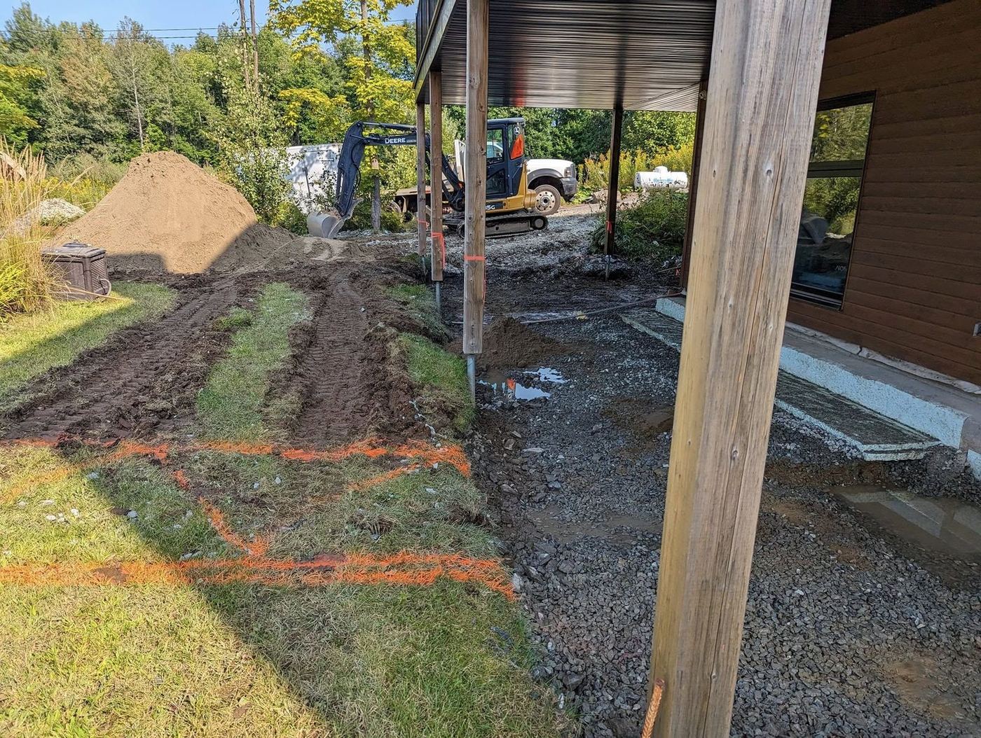 Tranchée de drainage résidentielle avec gravier et repères orange