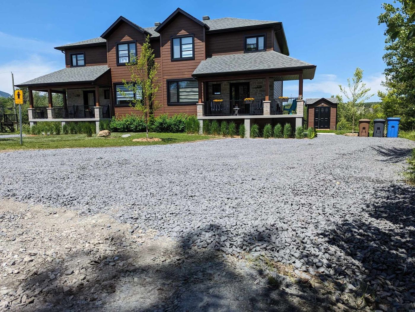 Entrée en gravier gris foncé compactée devant grande maison bois
