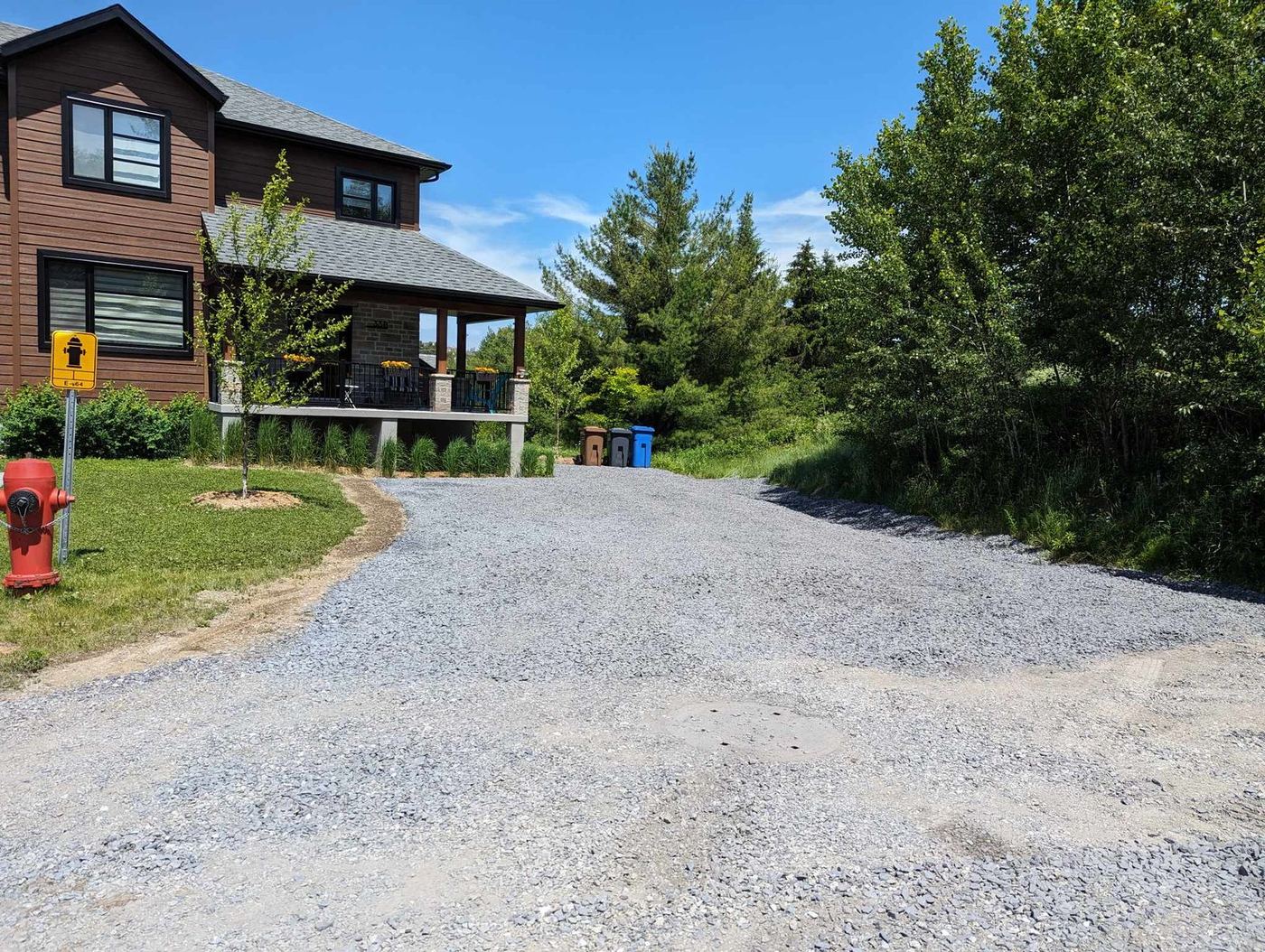 Entrée gravier résidentielle finie maison bois rouge