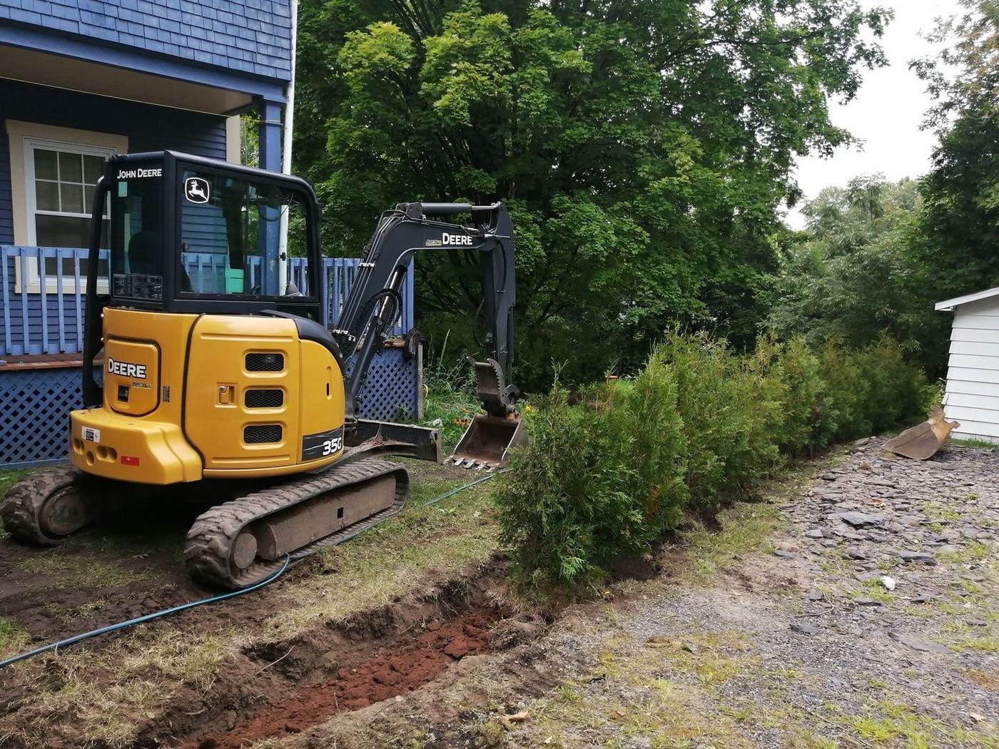 Mini-excavatrice Deere creuse tranchée drainage résidentiel cèdres