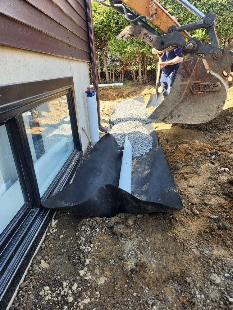 Drain français posé le long de fondation avec excavatrice en arrière-plan