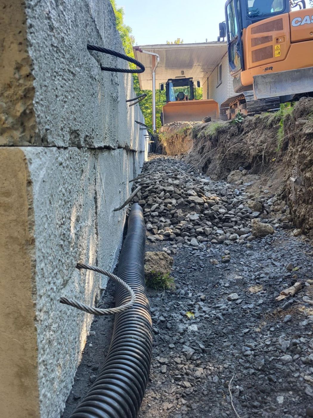 Drain français posé au pied de fondation béton, tranchée ouverte
