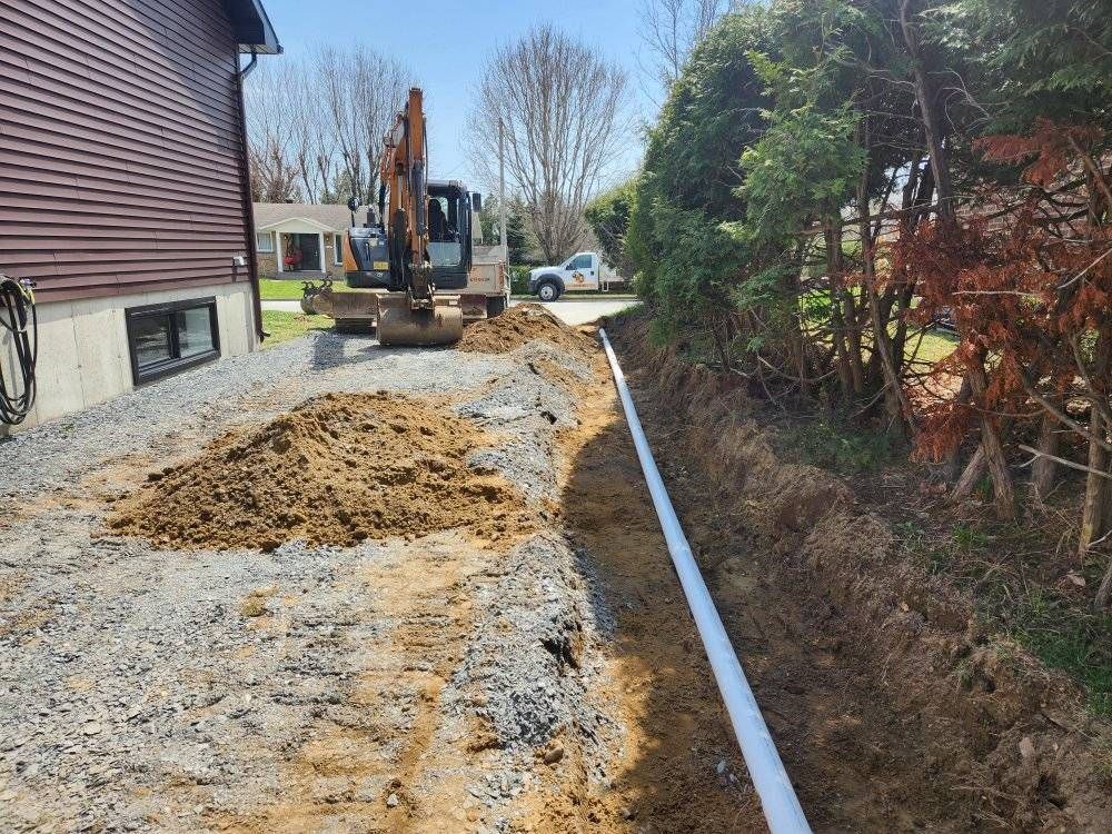 Tranchée drainage posée avec tuyau blanc le long bâtiment résidentiel