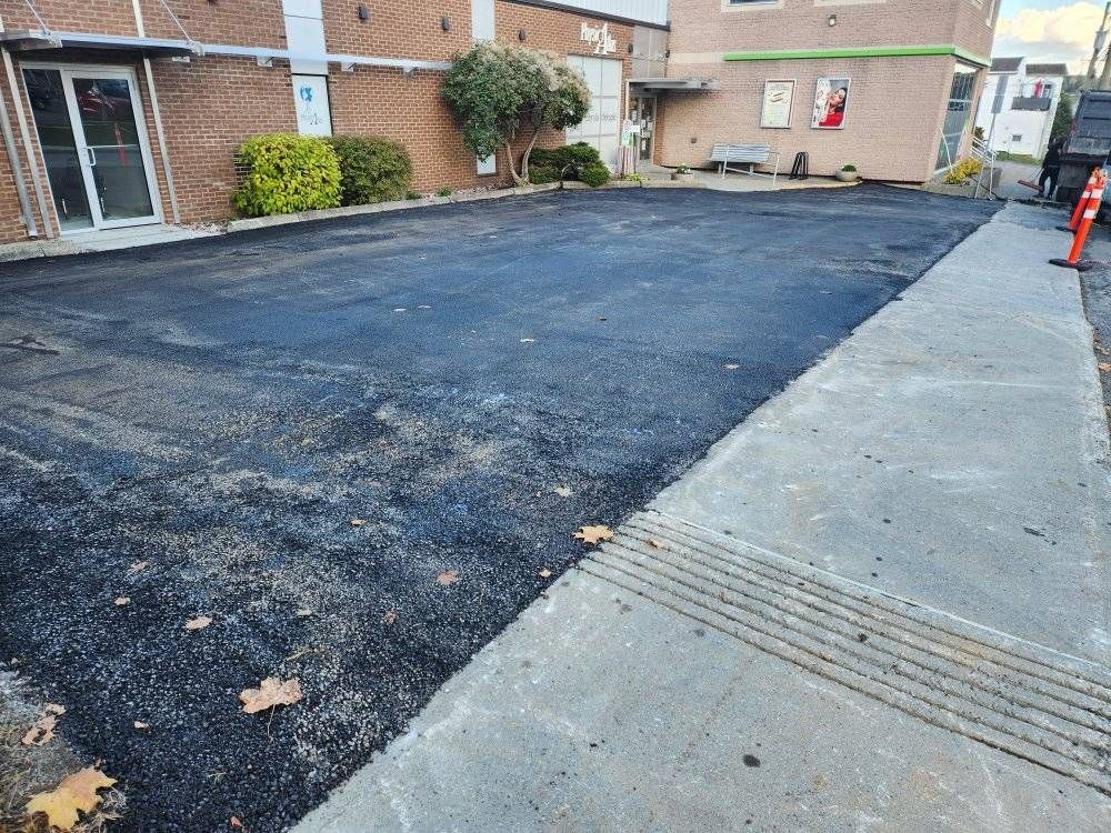 Stationnement commercial asphalté fraîchement, bâtiment de briques