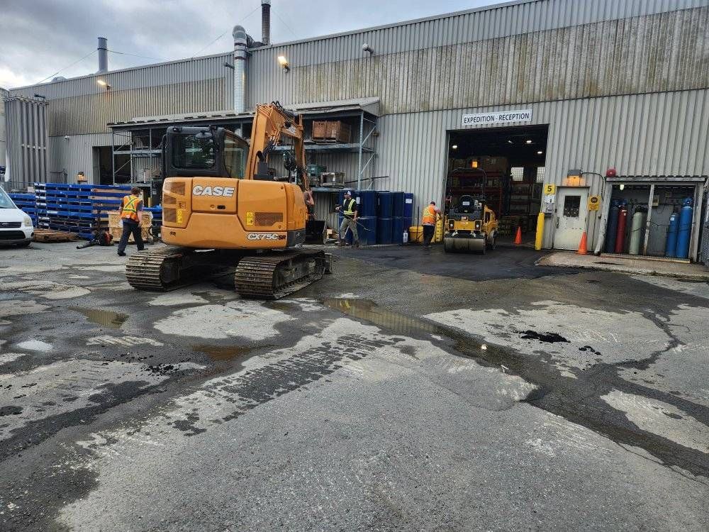 Excavatrice CASE sur chantier pavage industriel, bâtiment expédition