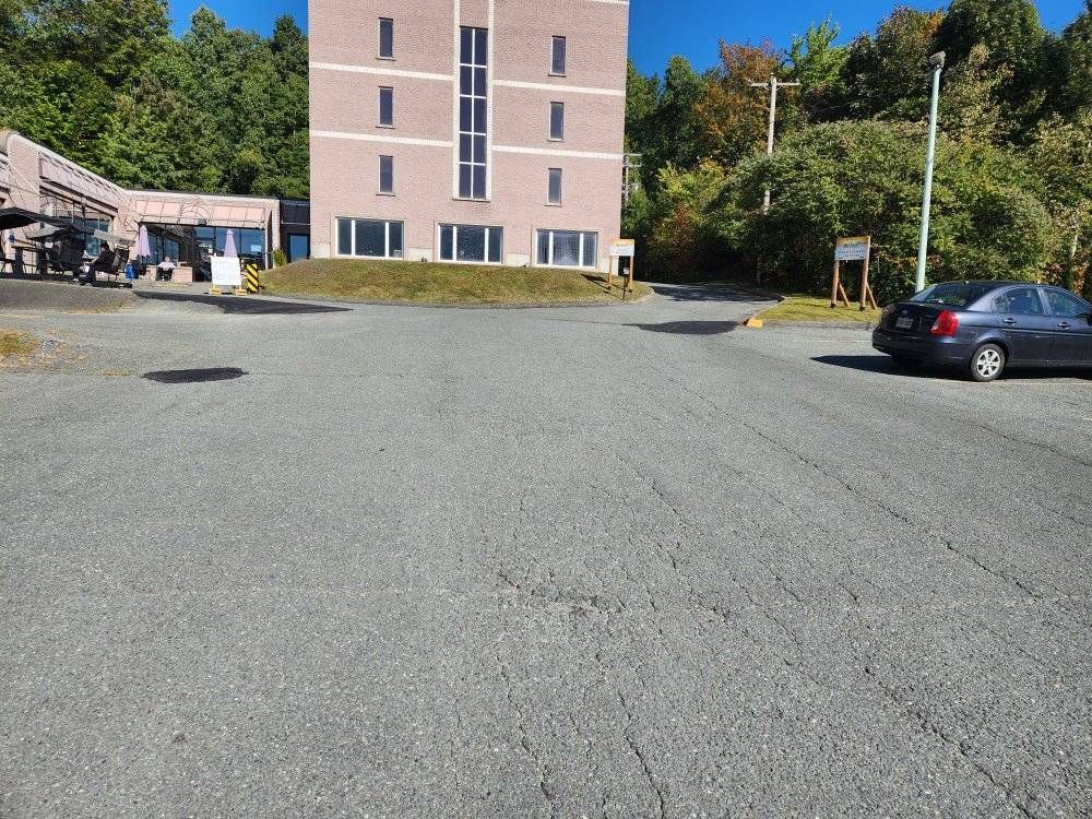 Stationnement commercial asphalte craquelée avant travaux, bâtiment 5 étages