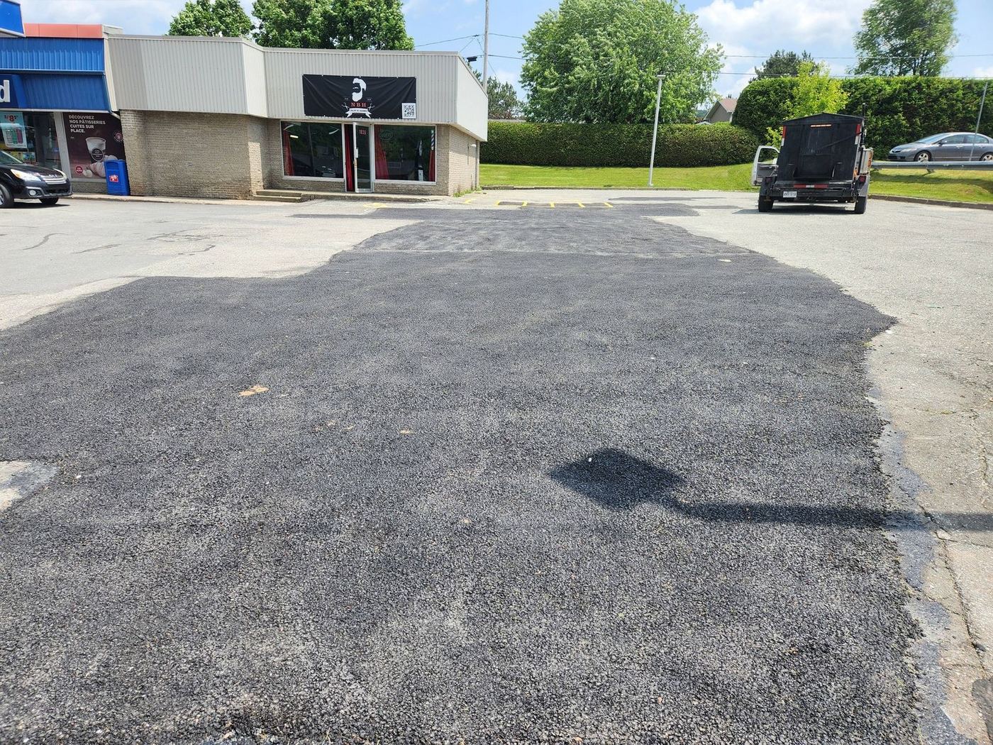 Stationnement commercial asphalté fraîchement, bâtiment commercial en fond