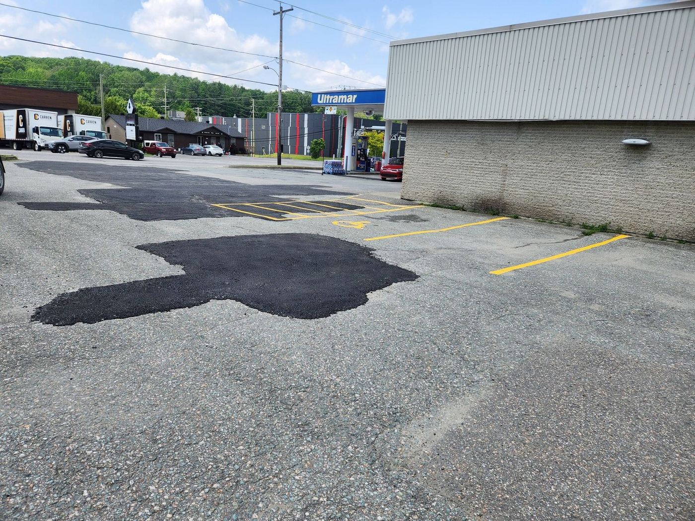 Réparation asphalte stationnement commercial Ultramar, patches irrégulières