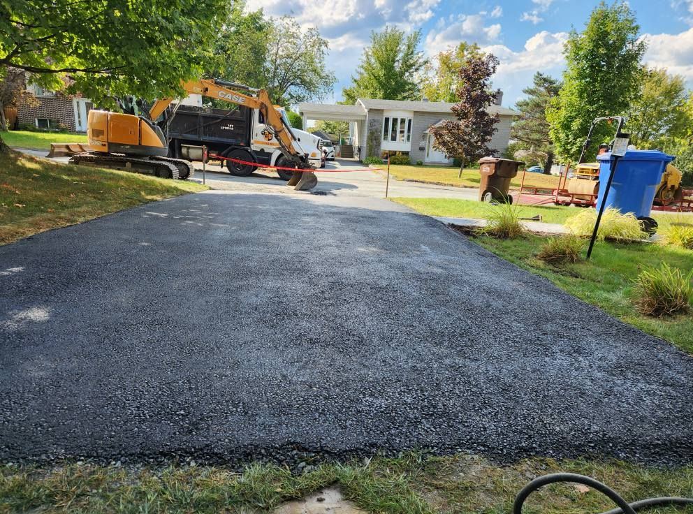 Asphalte fraîche sur entrée résidentielle, excavatrice en arrière-plan