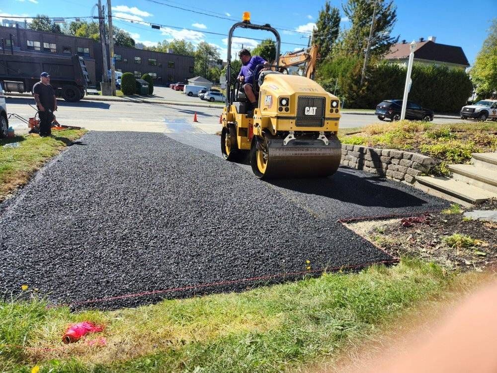Compacteur CAT sur asphalte fraîche, entrée résidentielle en cours