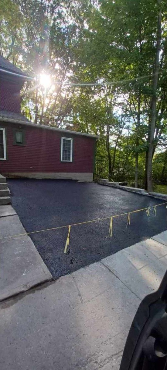 Nouvelle entrée asphaltée devant maison rouge en été