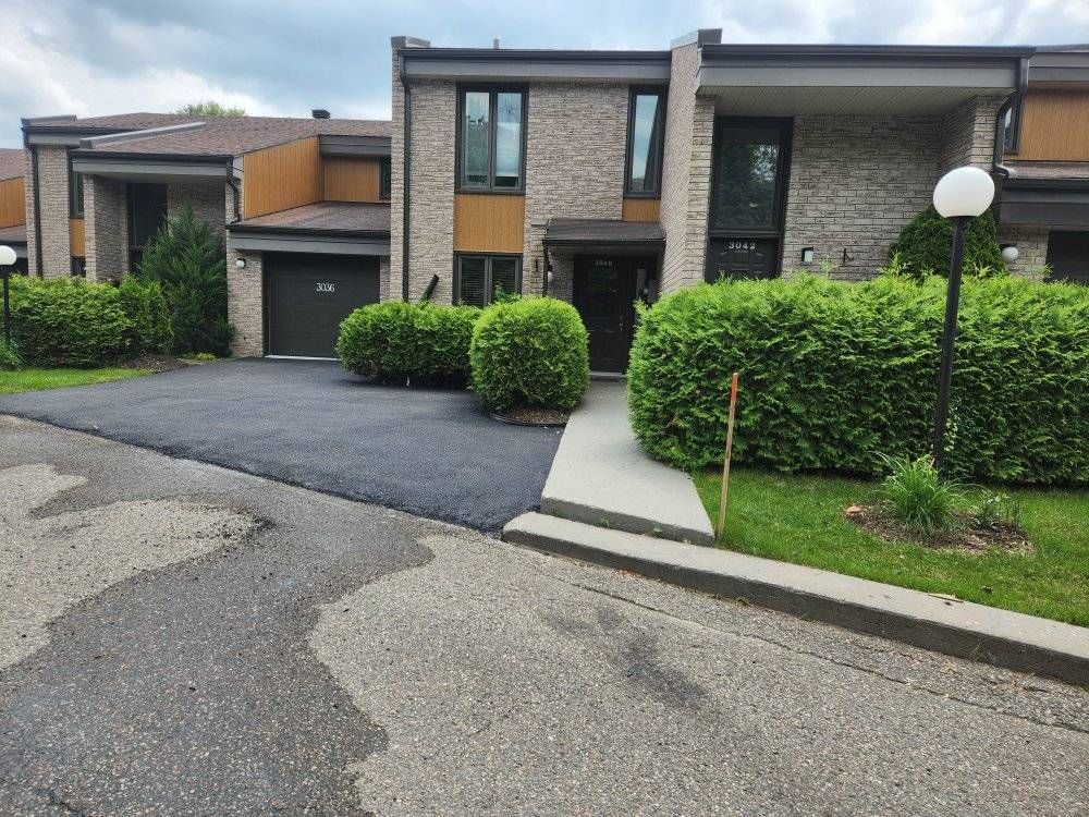 Entrée de condos asphaltée fraîche devant bâtiment multilogement