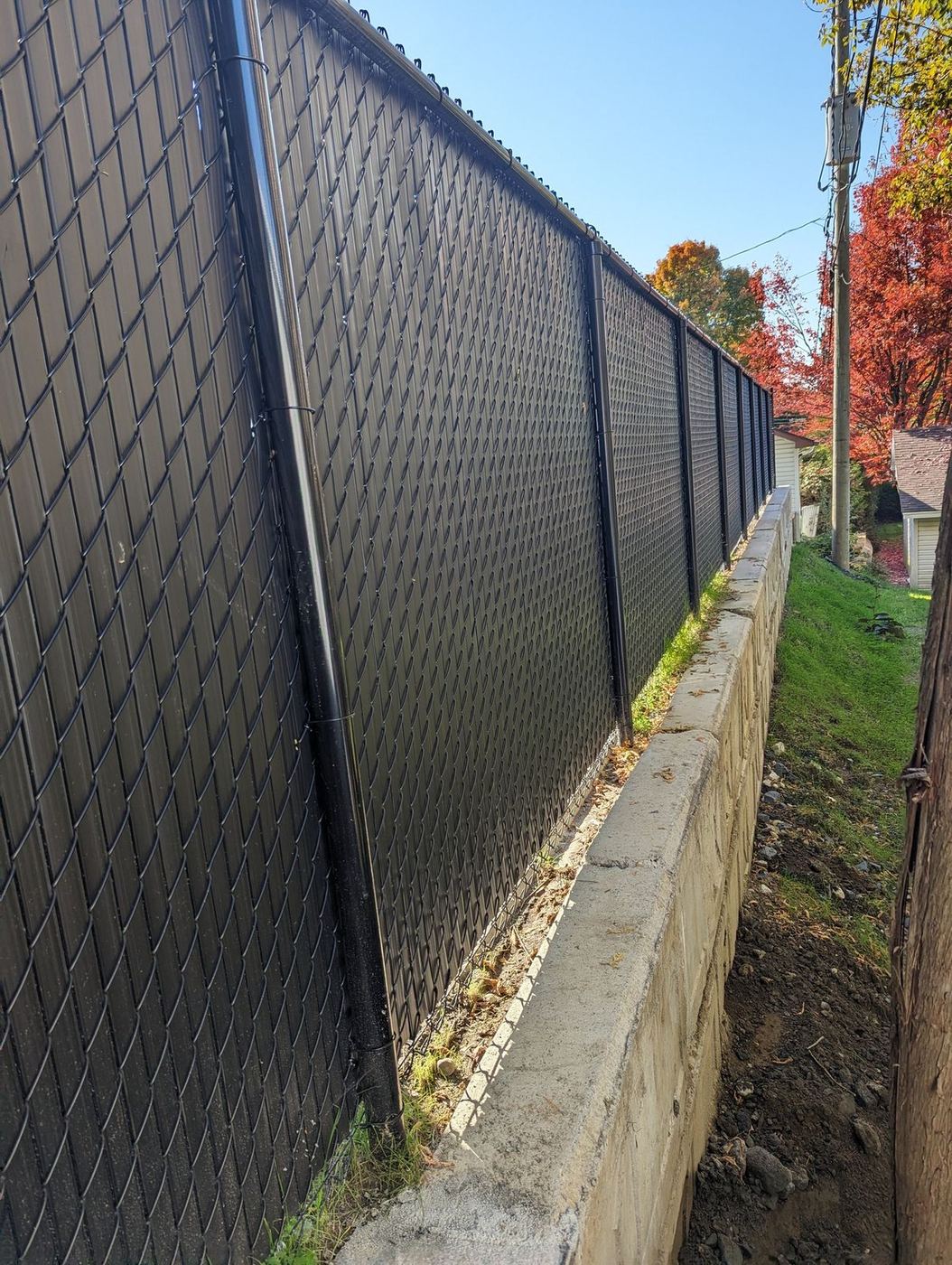 Long muret blocs béton avec clôture chainlink noire, résidentiel