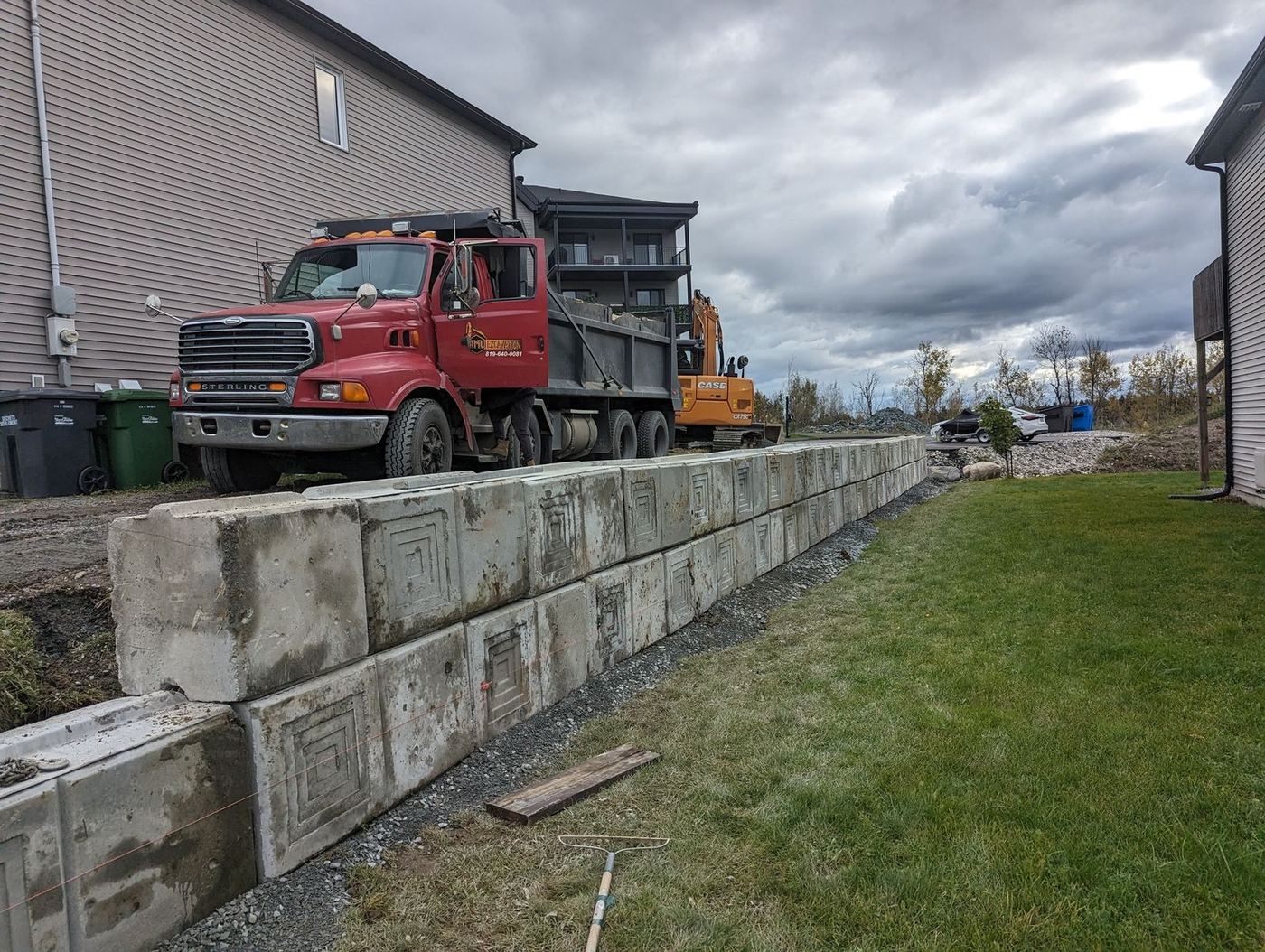 Muret de gros blocs béton avec camion-benne et excavatrice