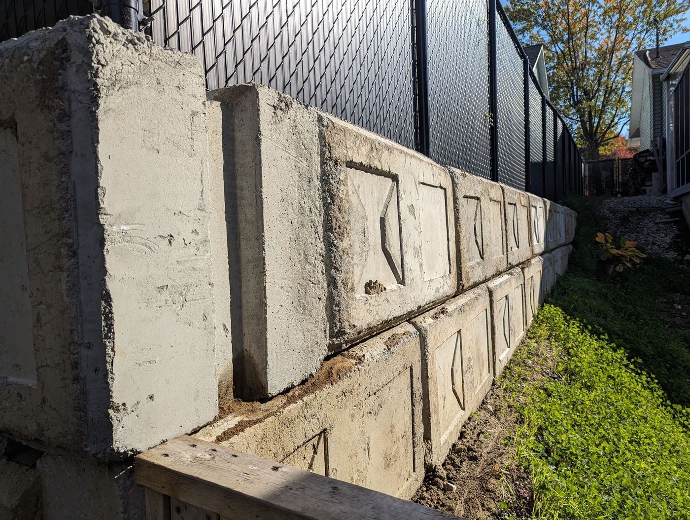 Gros plan muret blocs béton récents avec clôture en fond