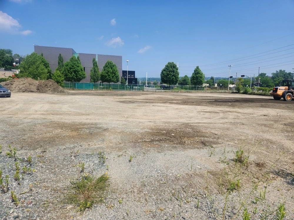 Vaste terrain commercial nivelé avec chargeur, bâtiment commercial en fond
