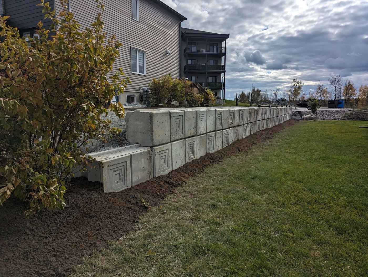 Muret blocs béton double rang derrière bâtiment résidentiel