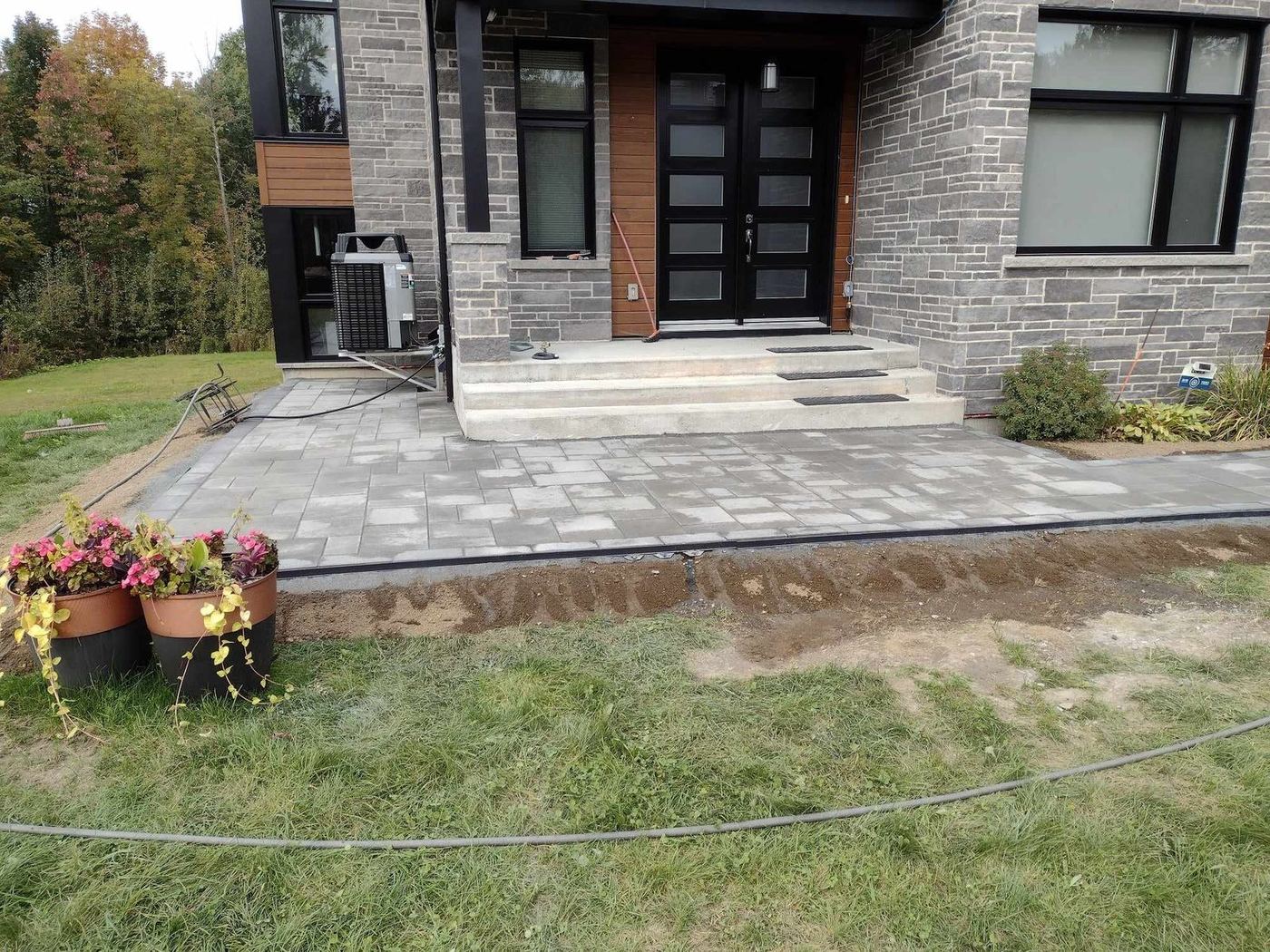 Dalle béton récente avec gravier devant maison bleue