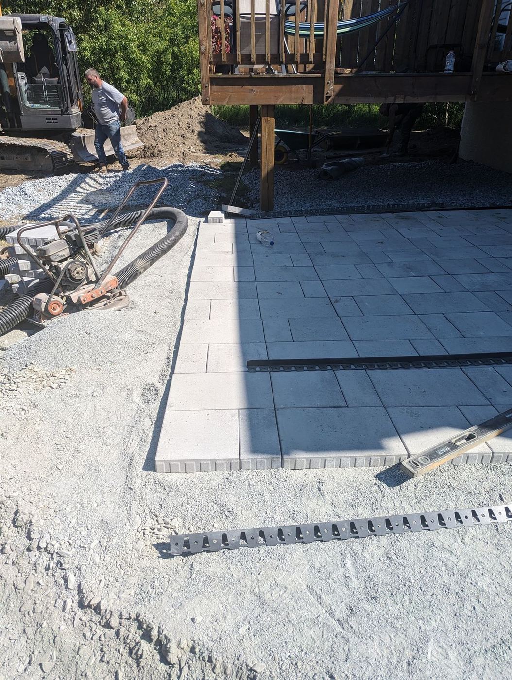Pose dalle patio en blocs gris ouvrier mini-excavatrice cour